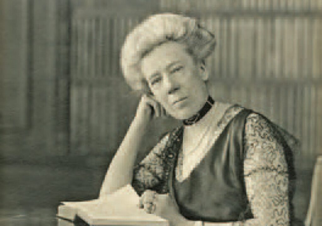 Photographic portrait of lady with lace and velvet dress and severe hair-do, reading a book.